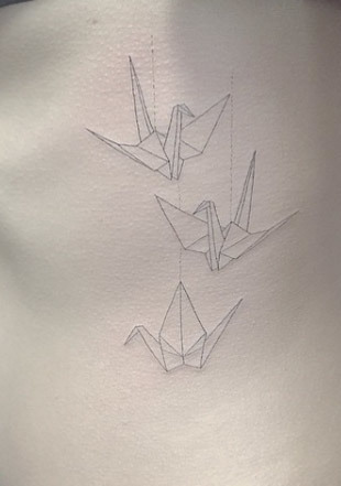 Tatuaggio origami con uccelli e gru sul lato di una donna